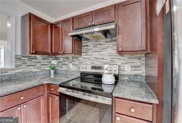 kitchen with light stone countertops, tasteful backsplash, under cabinet range hood, and stainless steel appliances