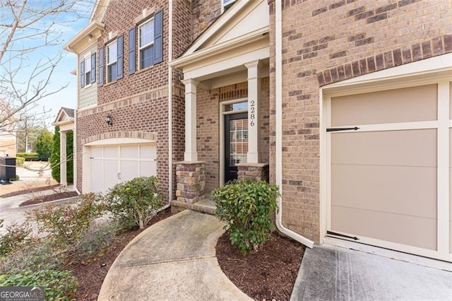 doorway to property with a garage and brick siding