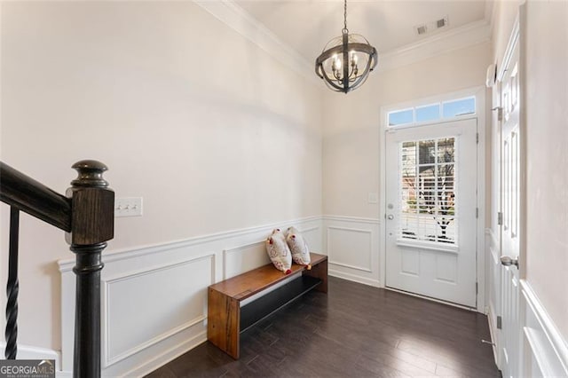 entrance foyer featuring visible vents, a wainscoted wall, dark wood-type flooring, crown molding, and a chandelier