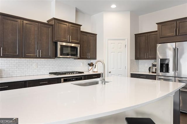 kitchen featuring a sink, light countertops, dark brown cabinets, appliances with stainless steel finishes, and tasteful backsplash