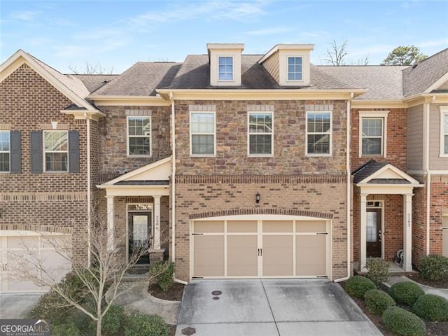 townhome / multi-family property featuring brick siding, stone siding, driveway, and an attached garage