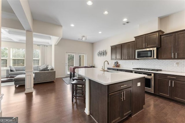 kitchen with backsplash, dark wood finished floors, decorative columns, stainless steel appliances, and a sink