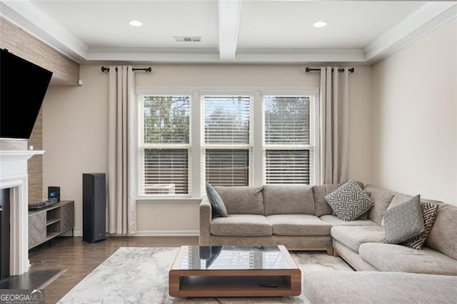 living room with visible vents, beamed ceiling, ornamental molding, wood finished floors, and a fireplace