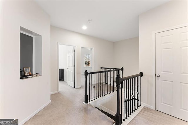 hallway with baseboards, an upstairs landing, and carpet floors