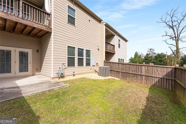 view of yard featuring central air condition unit, a balcony, french doors, and a fenced backyard