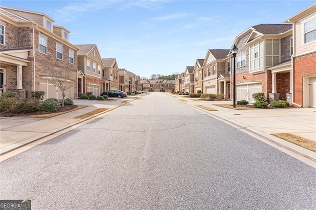 view of road with sidewalks, curbs, a residential view, and street lighting