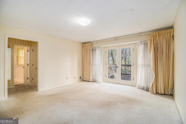 unfurnished room with baseboards, french doors, light colored carpet, and a textured ceiling
