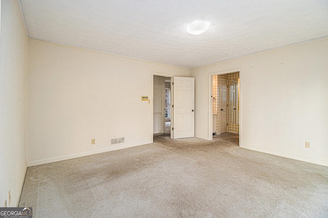 carpeted spare room featuring baseboards, visible vents, and ornamental molding