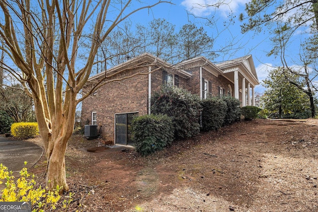 view of home's exterior with brick siding and central AC