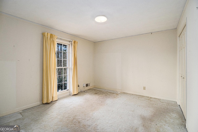 carpeted spare room with visible vents, baseboards, and crown molding