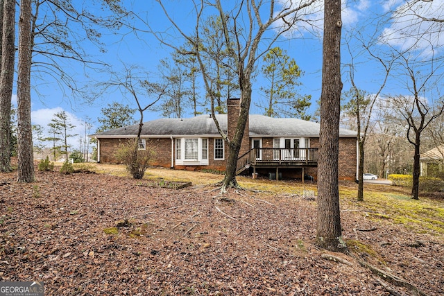 view of front facade with brick siding, a chimney, and a wooden deck