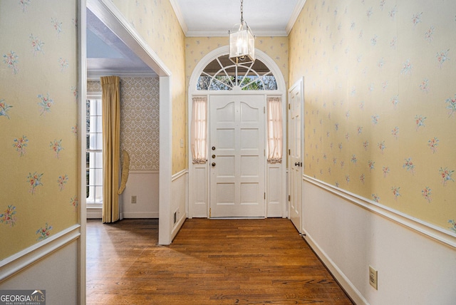 entrance foyer featuring wood finished floors, baseboards, wallpapered walls, an inviting chandelier, and crown molding