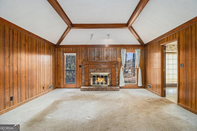 unfurnished living room featuring carpet, lofted ceiling with beams, wooden walls, and a fireplace