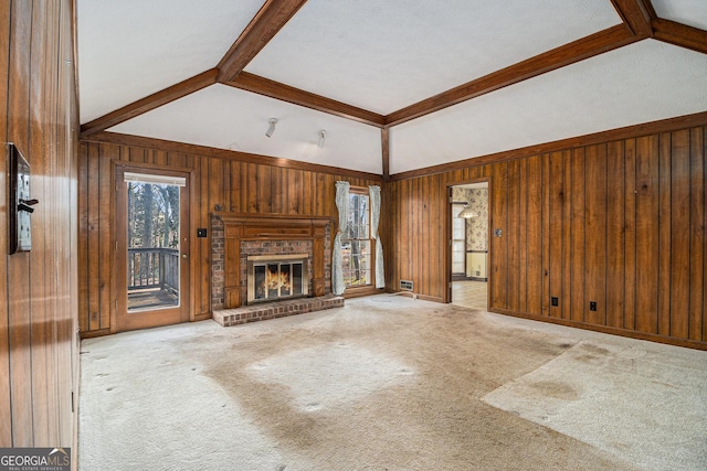unfurnished living room with a brick fireplace, wooden walls, and a healthy amount of sunlight