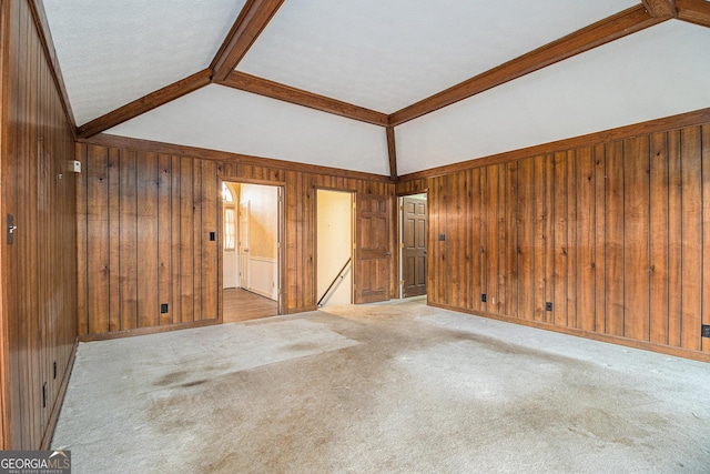spare room with wooden walls, vaulted ceiling with beams, carpet, and baseboards