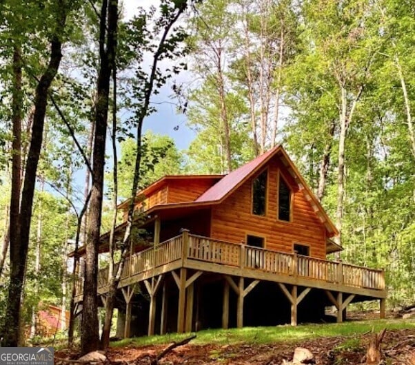 back of property with a deck and a forest view