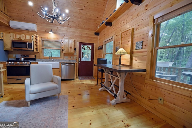 kitchen with an AC wall unit, an inviting chandelier, wood walls, appliances with stainless steel finishes, and a sink