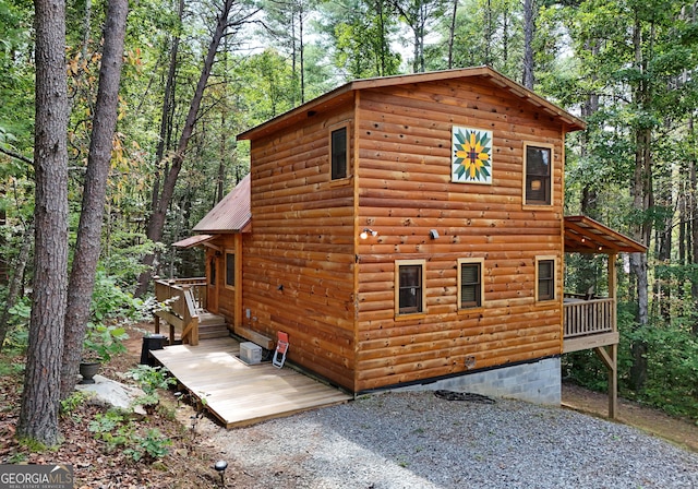 view of side of property with metal roof, a deck, and log veneer siding
