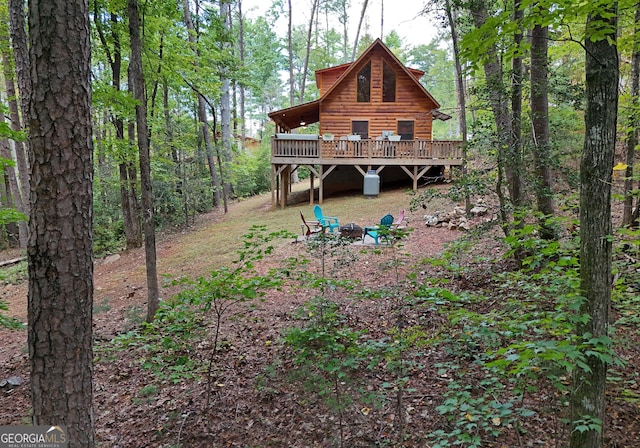 back of house featuring a deck, faux log siding, and a fire pit