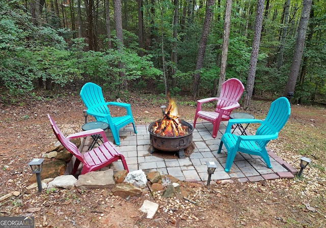 view of patio / terrace featuring an outdoor fire pit and a view of trees