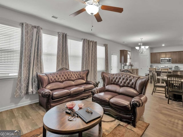 living area featuring recessed lighting, baseboards, light wood-style floors, and ceiling fan with notable chandelier