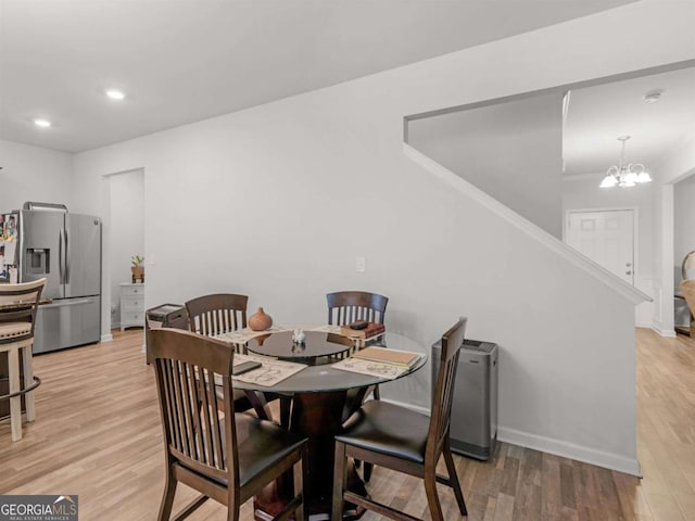 dining space featuring light wood-style flooring, a notable chandelier, recessed lighting, and baseboards