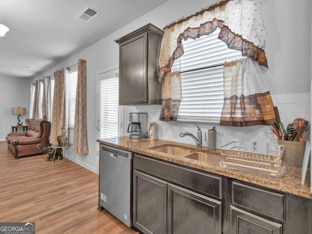 kitchen featuring light stone countertops, visible vents, light wood-style flooring, a sink, and stainless steel dishwasher