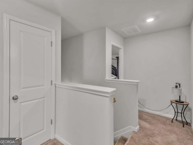 hallway featuring baseboards, an upstairs landing, and carpet