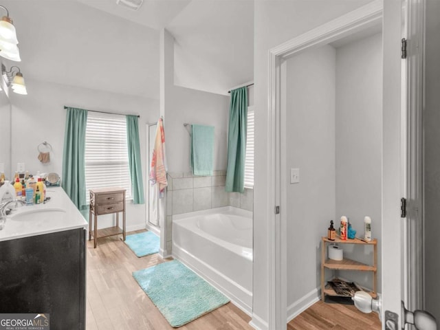 bathroom featuring a sink, baseboards, wood finished floors, and a bath