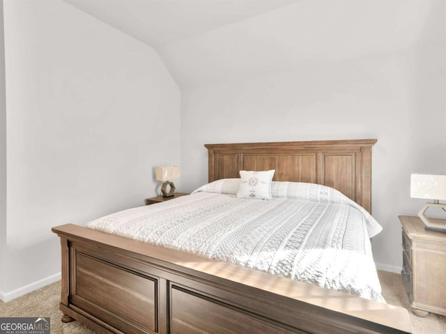 bedroom featuring lofted ceiling, baseboards, and light carpet