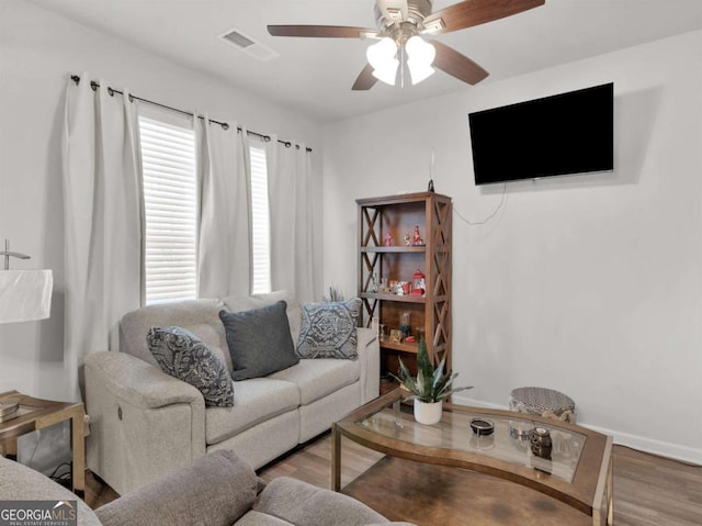 living area featuring visible vents, baseboards, ceiling fan, and wood finished floors