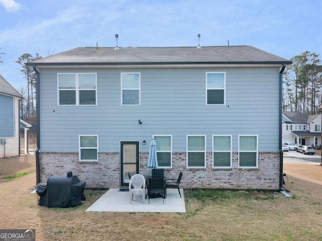 back of property with a patio, a lawn, and brick siding