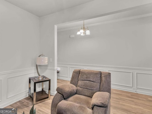 living area featuring a decorative wall, an inviting chandelier, and wood finished floors