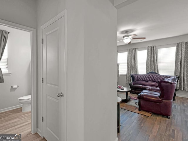 living room featuring light wood-type flooring, baseboards, and ceiling fan