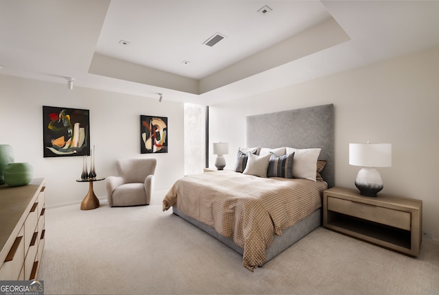 bedroom featuring a raised ceiling, light colored carpet, visible vents, and baseboards