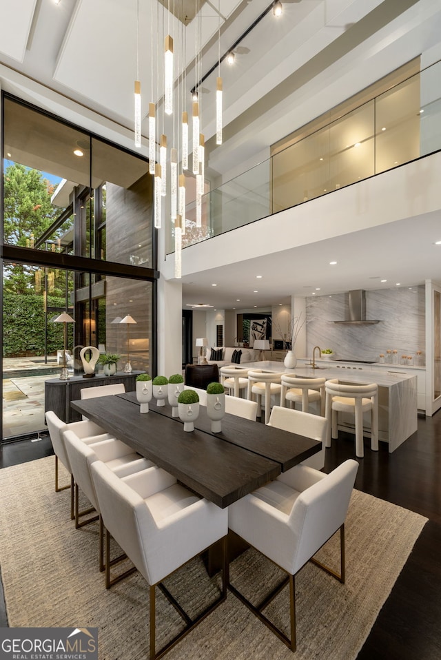 dining room with a wall of windows, dark wood-type flooring, and a towering ceiling