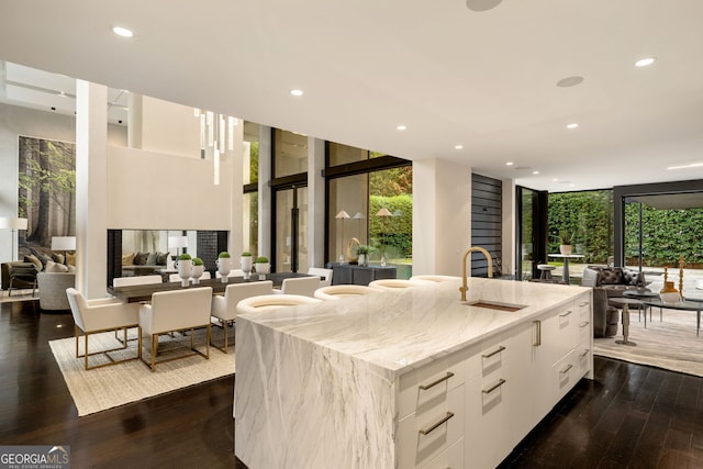 kitchen featuring open floor plan, expansive windows, light stone counters, white cabinetry, and modern cabinets