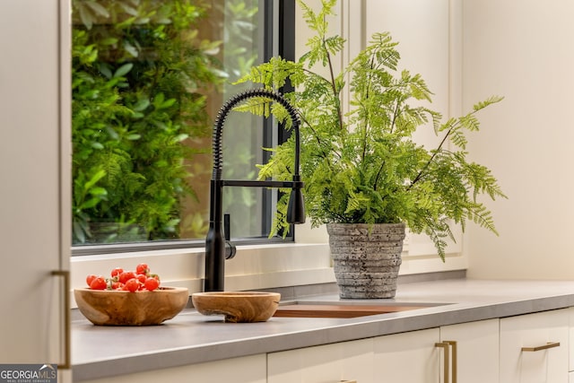 room details with a sink, white cabinets, and stainless steel counters