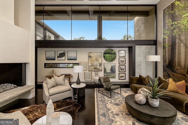 living area featuring a fireplace with raised hearth, a high ceiling, and expansive windows