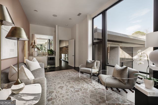 living room featuring wood finished floors, plenty of natural light, beverage cooler, and visible vents