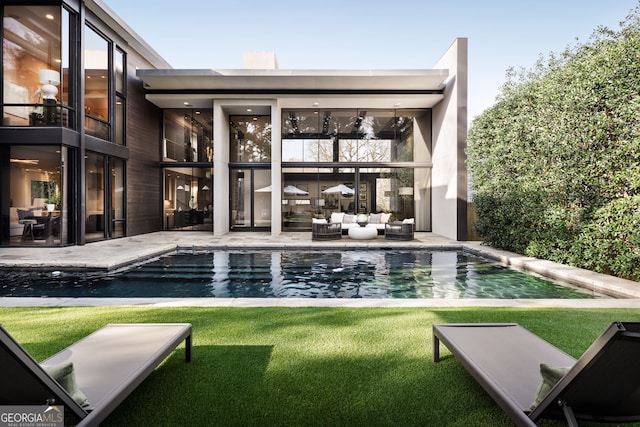 rear view of property featuring a lawn, outdoor lounge area, a balcony, an outdoor pool, and a patio