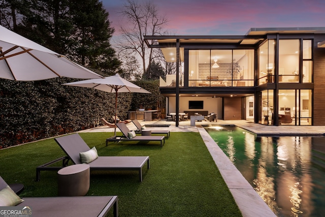 back of house featuring an outdoor living space, a lawn, a balcony, a patio area, and an outdoor pool