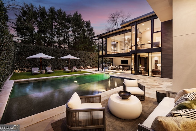 pool at dusk featuring an outdoor living space, a patio area, and an outdoor pool