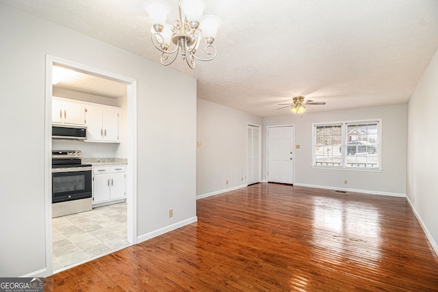 unfurnished living room featuring light wood finished floors, ceiling fan with notable chandelier, a textured ceiling, and baseboards