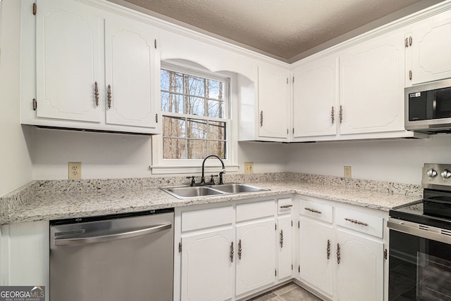 kitchen with white cabinets, appliances with stainless steel finishes, a textured ceiling, and a sink