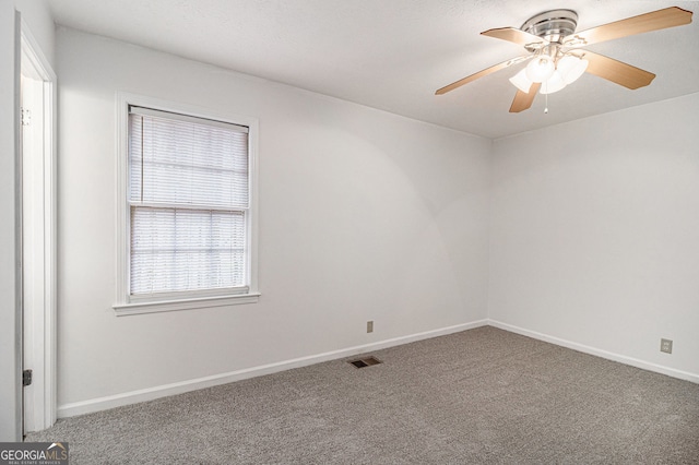 carpeted empty room featuring visible vents, baseboards, and a ceiling fan