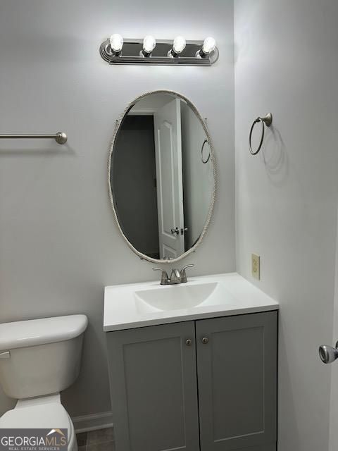 bathroom with baseboards, toilet, and vanity