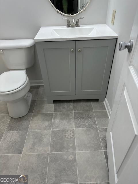 bathroom with tile patterned flooring, toilet, vanity, and baseboards