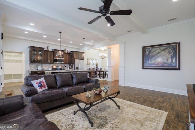 living area with visible vents, beam ceiling, ornamental molding, wood finished floors, and baseboards