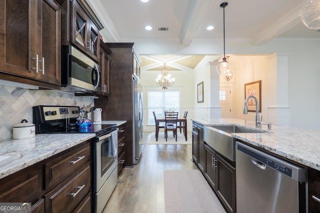 kitchen featuring visible vents, beamed ceiling, ornamental molding, appliances with stainless steel finishes, and light wood-style floors